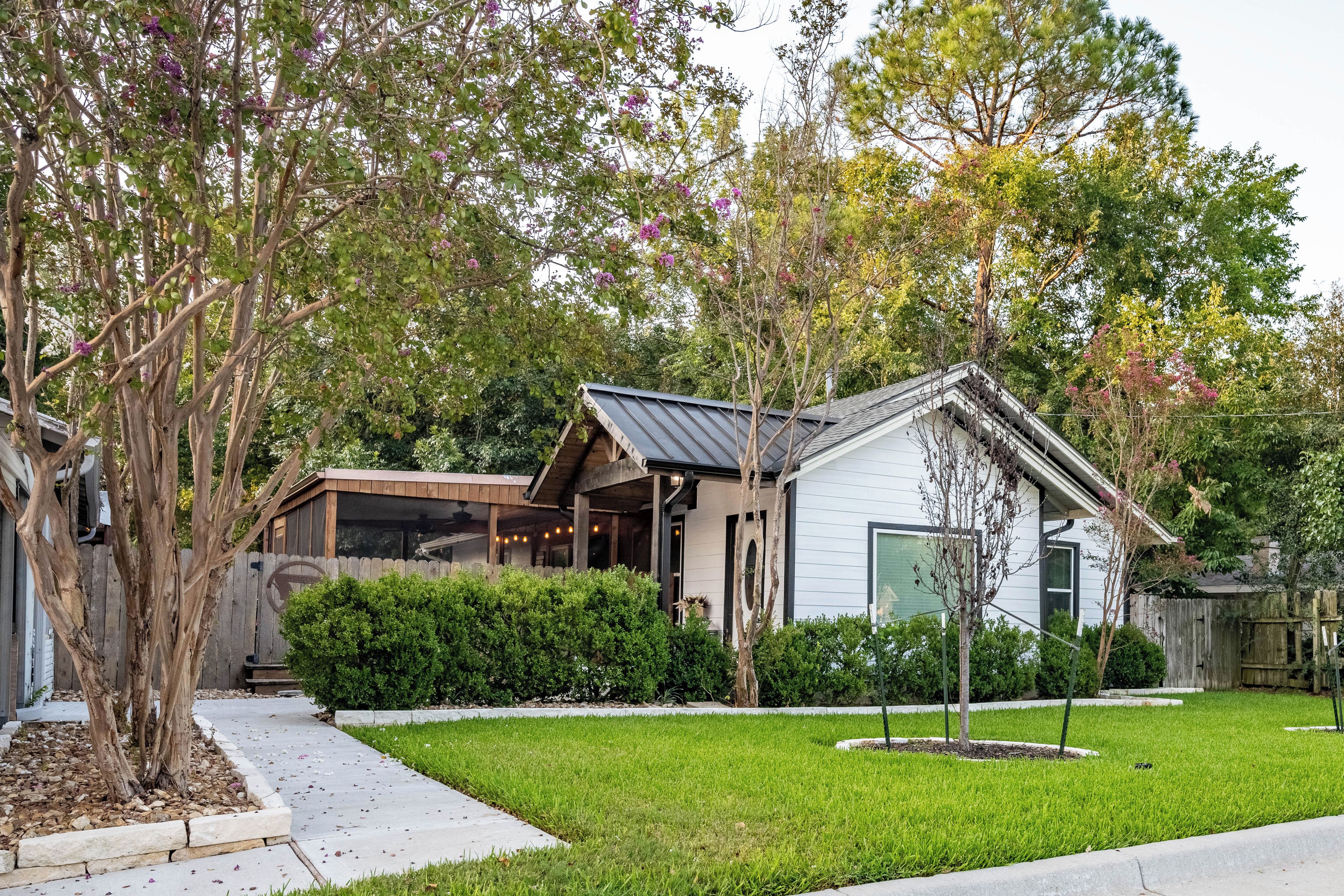 A residential house with a covered porch, a well-maintained lawn, and mature trees.