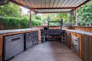 An outdoor kitchen with a grill, storage cabinets, and a wooden deck.