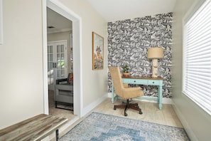 A room with a desk, chair, and a patterned wallpaper. - Hot Tub + Outdoor Kitchen: Stylish Home in Bryan (Bryan)