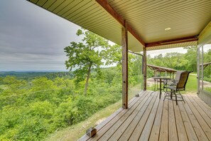 Une terrasse en bois avec une table et des chaises, offrant une vue sur un paysage verdoyant et luxuriant.