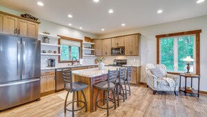 A modern kitchen with wooden cabinets, stainless steel appliances, and a central island with bar stools. - Ski, Ice Fish & Snowshoe: Mindoro Getaway! (Mindoro)