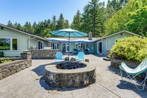 A house with a stone fire pit, blue chairs, and a large umbrella. - Oregon Farmhouse Hideaway on 53 Acres (Springfield)