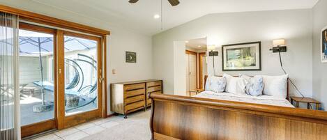 A bedroom with a wooden bed, a ceiling fan, and a sliding glass door leading to a patio.