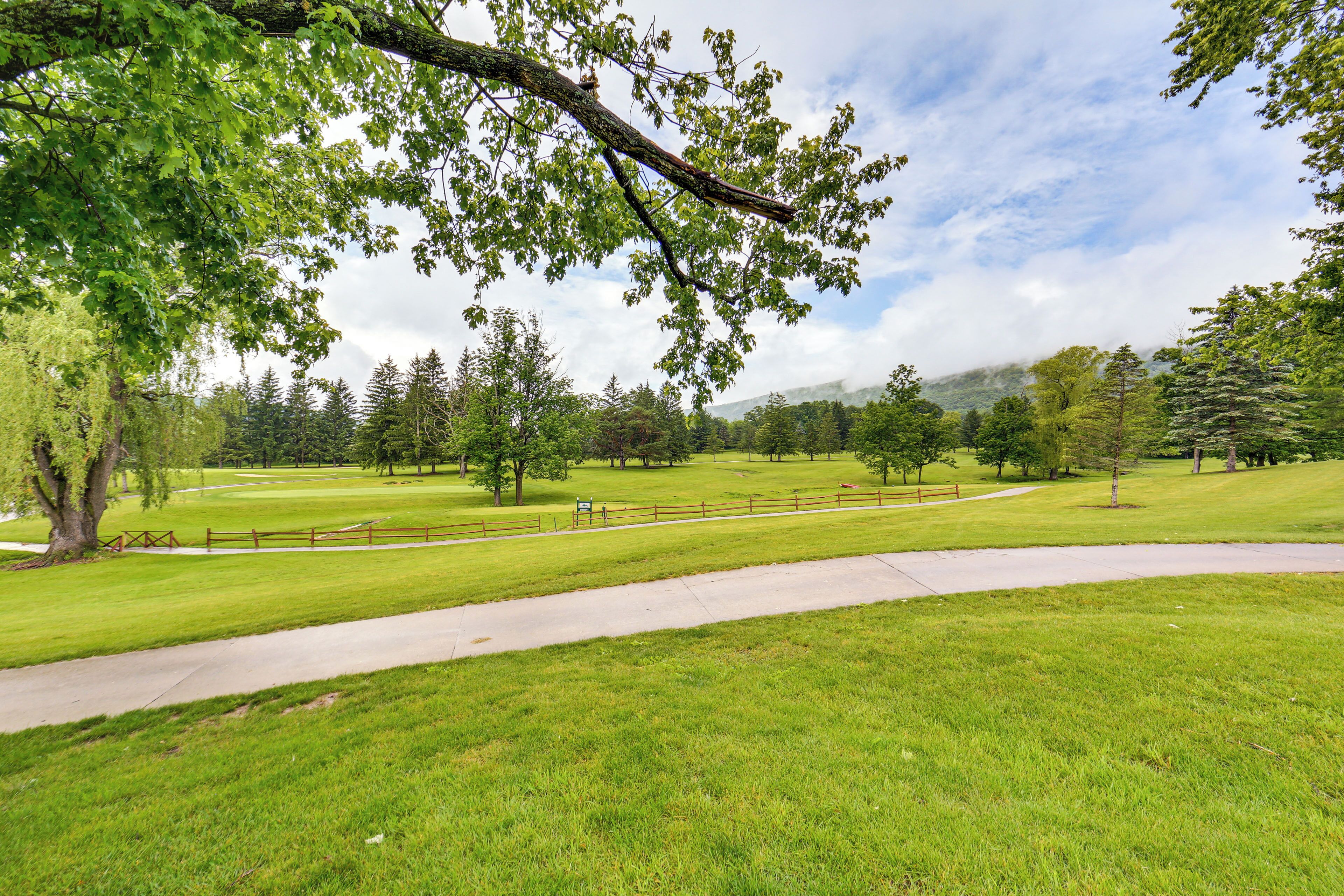 Ein Park mit einem gepflasterten Weg, Rasenflächen und Bäumen.