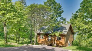 A log cabin with a wooden deck and a front porch, surrounded by lush green trees. - Bluff Views: 'bunker Hill' Cabin in Mindoro! (Mindoro)