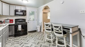 A kitchen with a microwave, oven, and two chairs at a small table. - 14 Mi to Downtown Baton Rouge: Plaquemine Retreat (Plaquemine)