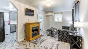 A living room with a fireplace, a sofa, a coffee table, and a TV mounted on the wall. - 14 Mi to Downtown Baton Rouge: Plaquemine Retreat (Plaquemine)