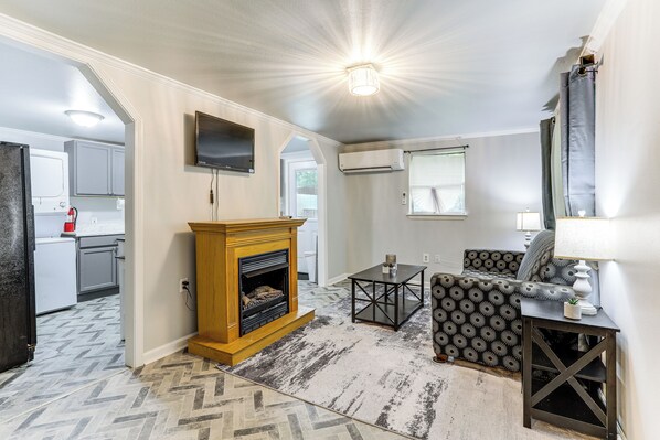 A living room with a fireplace, a sofa, a coffee table, and a TV mounted on the wall. - 14 Mi to Downtown Baton Rouge: Plaquemine Retreat (Plaquemine)