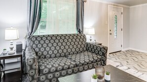 A living room with a patterned sofa, a coffee table, two lamps, and a door with a stained glass window. - 14 Mi to Downtown Baton Rouge: Plaquemine Retreat (Plaquemine)