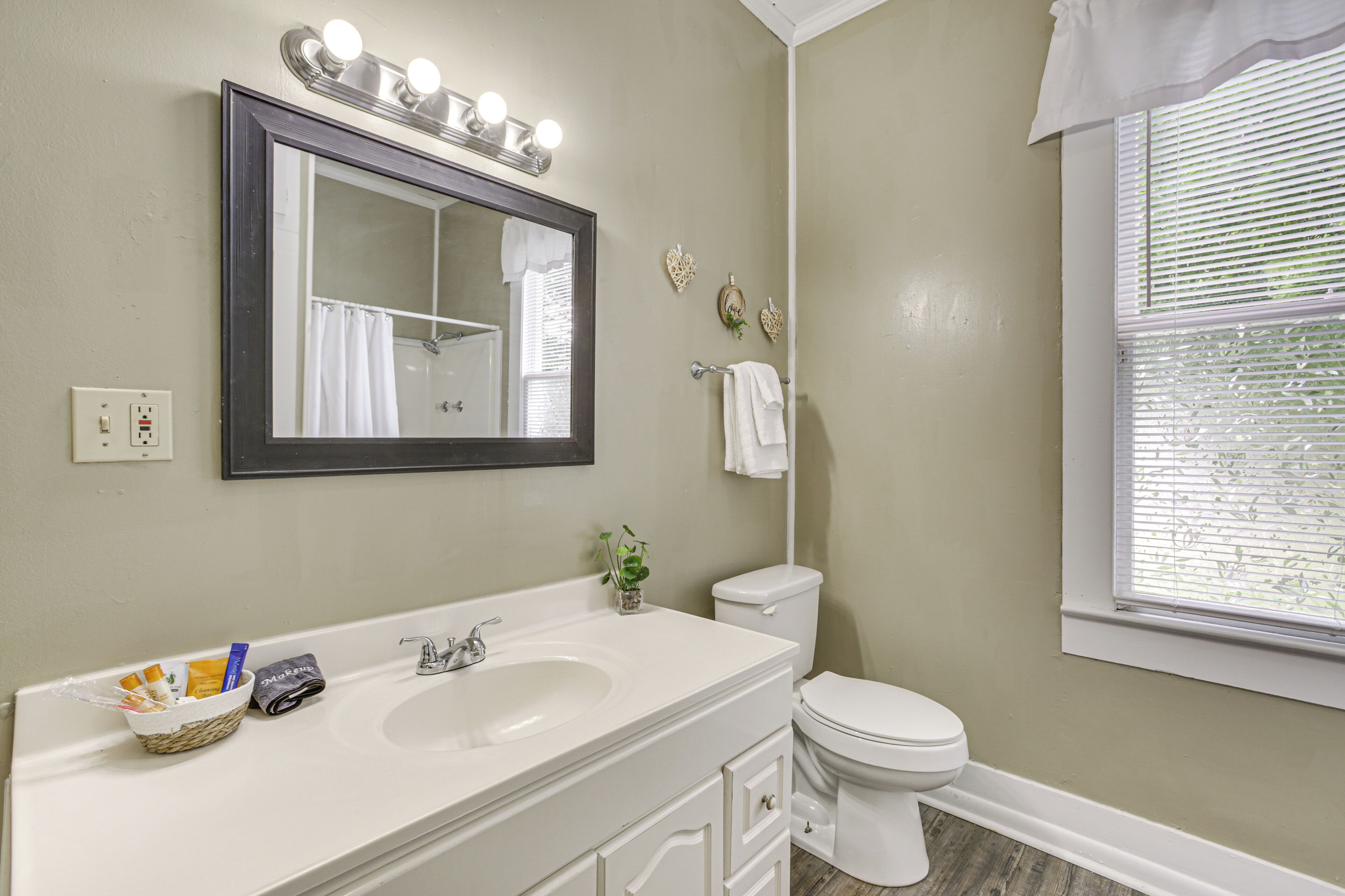 A bathroom with a vanity, sink, mirror, and toilet.