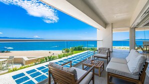 A balcony with a view of the sea, outdoor furniture, and a pool area. - Beachfront, Private Pool, Theatre Room, Views! (Puerto Vallarta)