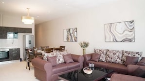 Uma sala de estar moderna com um sofá marrom, uma mesa de centro de vidro e um espaço de jantar com mesa e cadeiras de madeira.
