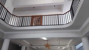 Un interior de varios niveles con barandilla de balcón curva, una araña y un techo con columnas.