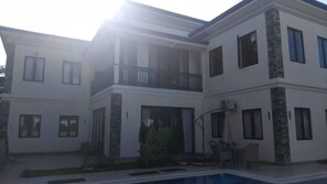 Ein zweistöckiges Haus mit Swimmingpool, Balkon und einer Terrasse.