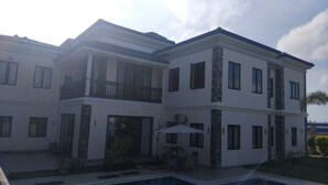 Un edificio residencial de dos pisos con balcón, piscina y mobiliario exterior.