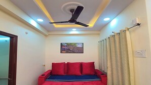 Une chambre à coucher comprenant un lit, un ventilateur de plafond, un éclairage encastré et un tableau accroché au mur.