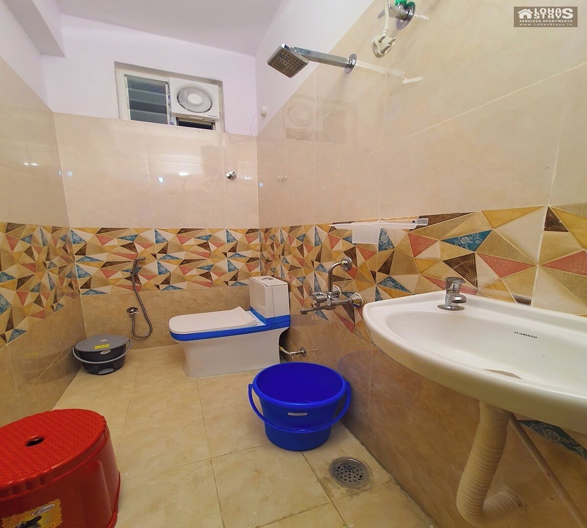 A bathroom with a toilet, bidet, sink, shower, and tiled walls.