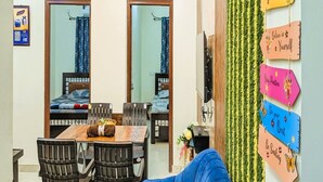 Un coin repas avec une table et des chaises en bois, un canapé bleu et un mur orné de panneaux d’affichage aux messages inspirants.