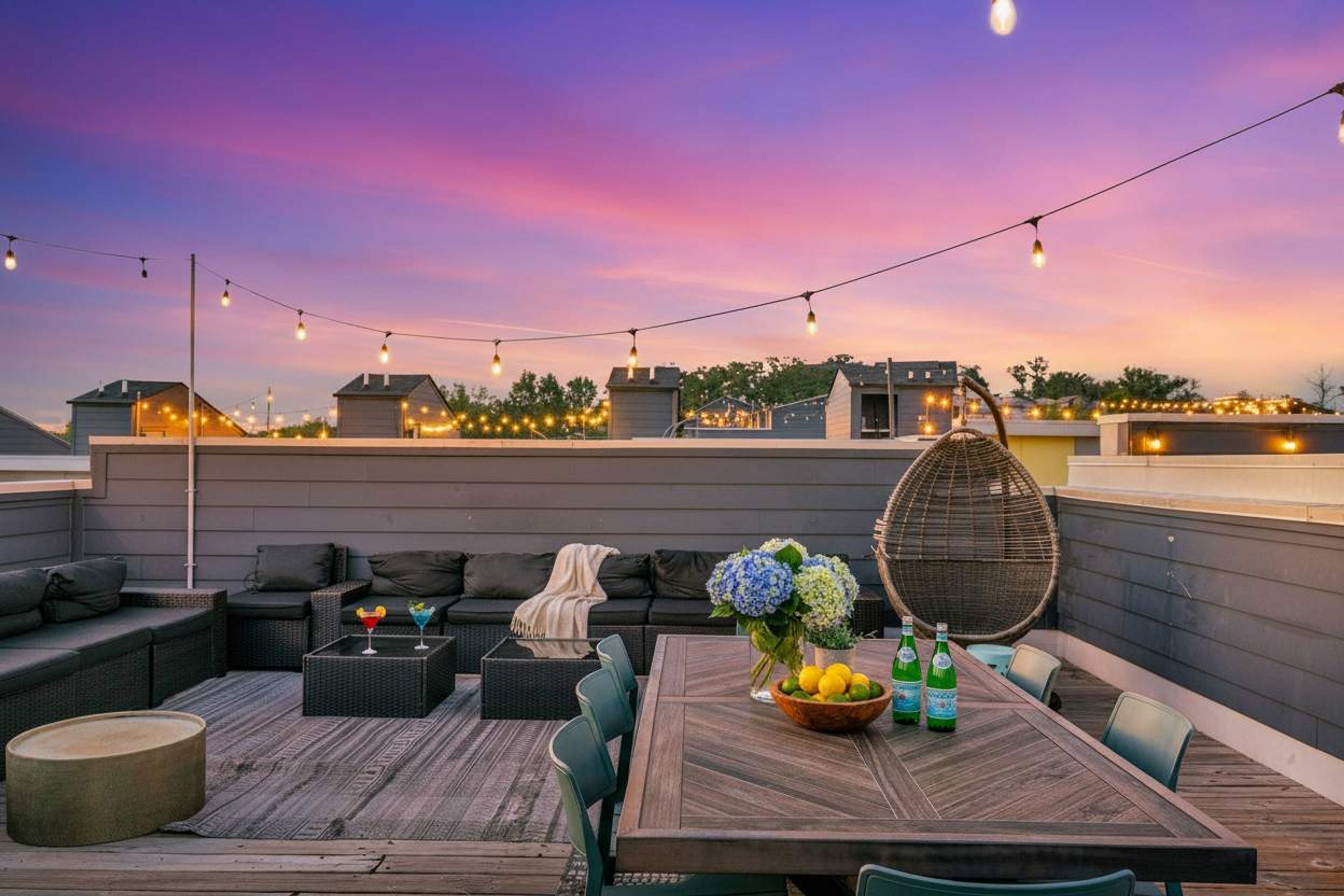 Une terrasse sur le toit avec une table en bois, des chaises et un fauteuil en osier.