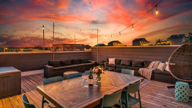 A rooftop patio with a wooden table, chairs, and a seating area with cushions. - Rooftop Deck 2 Car Garage Near Downtown Nashville (Nashville)