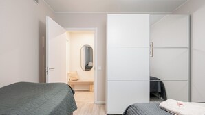 A bedroom with two beds, a wardrobe, a bench, and a mirror.