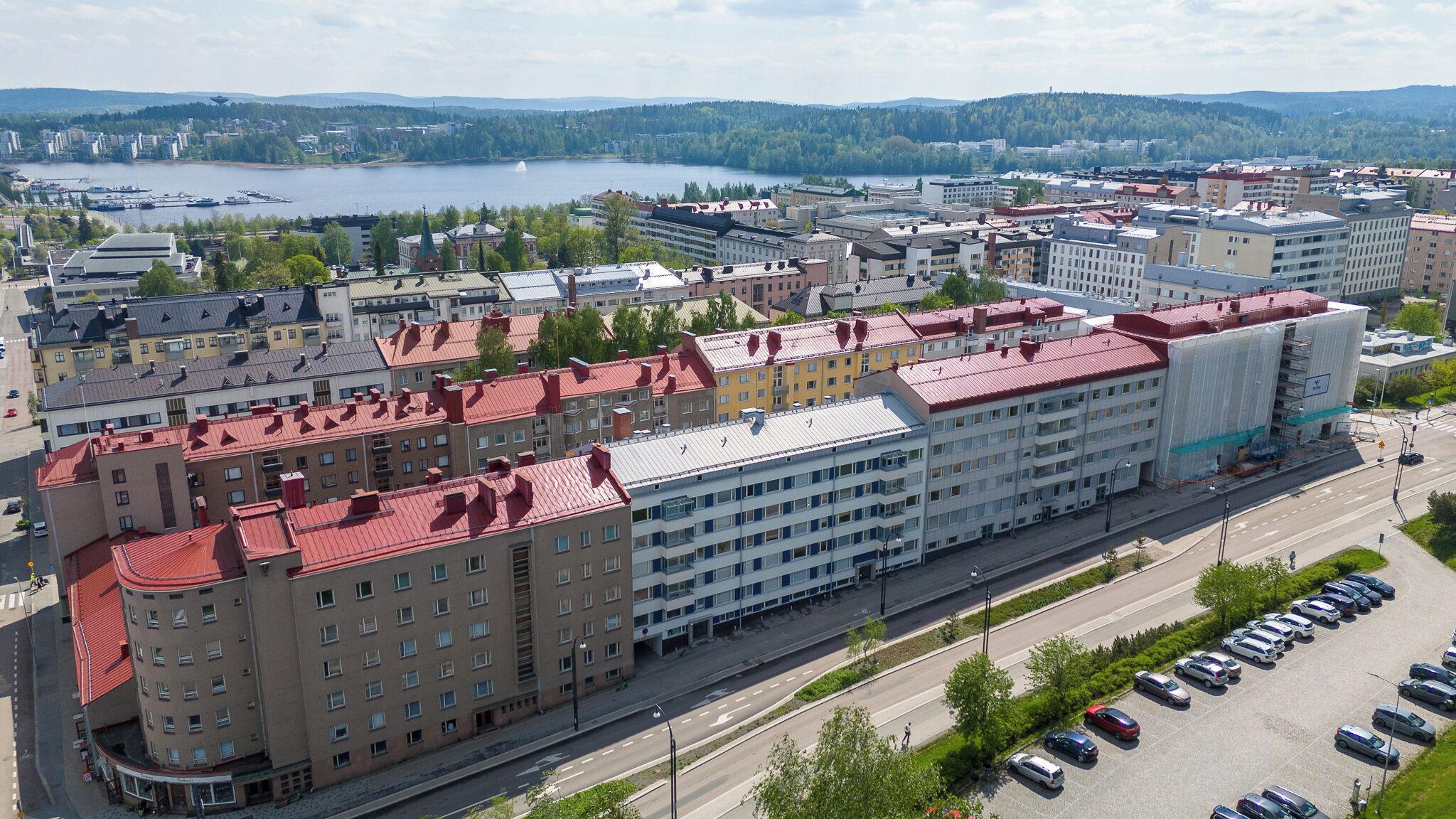 A multi-story hotel with a red roof, located near a body of water and surrounded by other buildings.