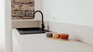A kitchen with a stone backsplash, a black faucet, and three bowls on a wooden tray.