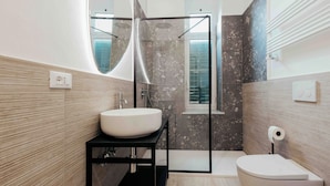 A modern bathroom with a large mirror, a sink, a toilet, and a shower area.