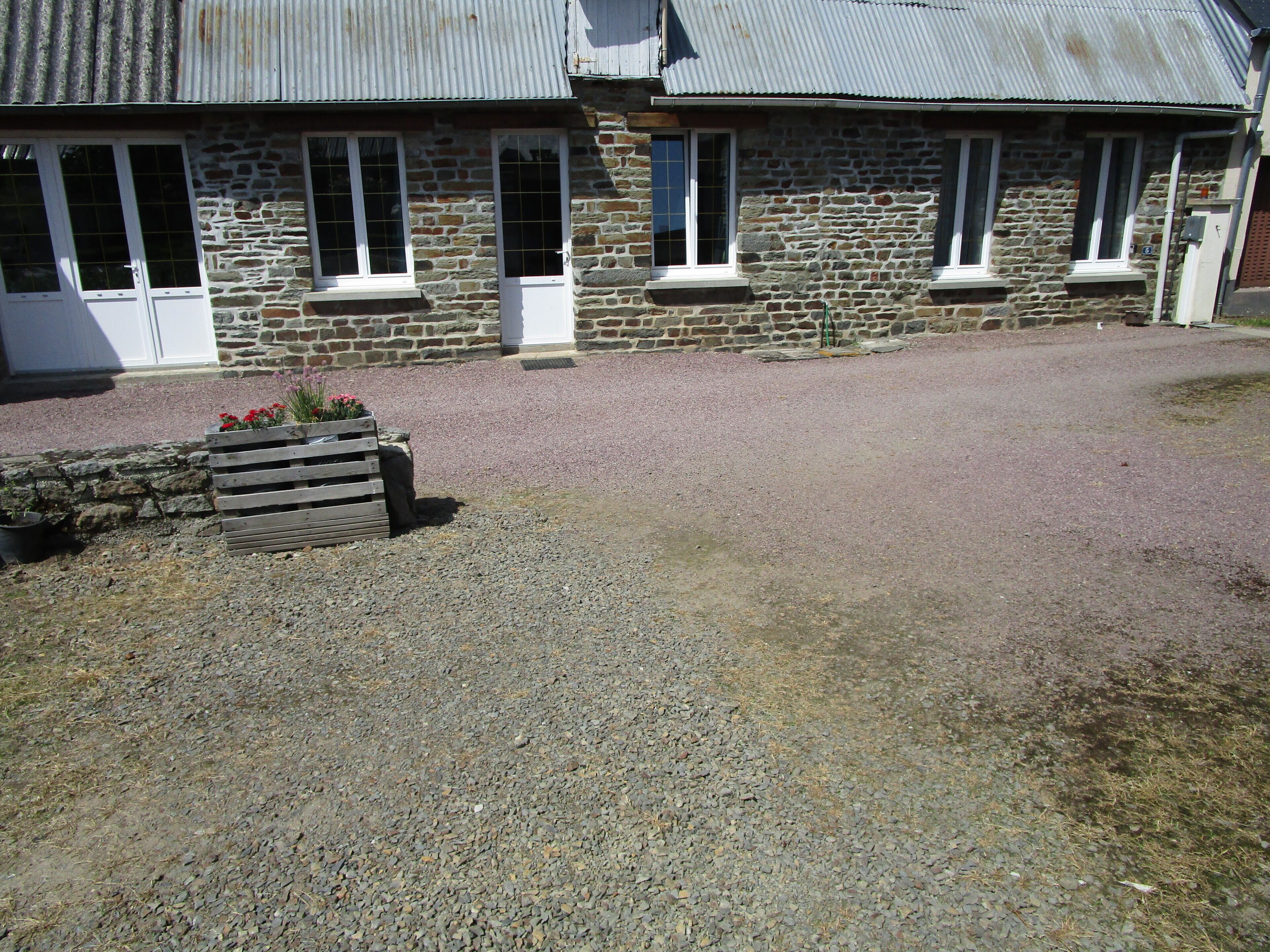 A stone building with multiple windows and a gravel driveway.