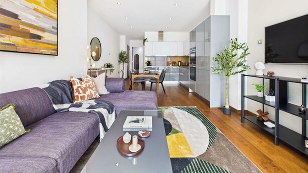 Un salon moderne comprenant un canapé, une table basse et un coin repas avec des chaises.