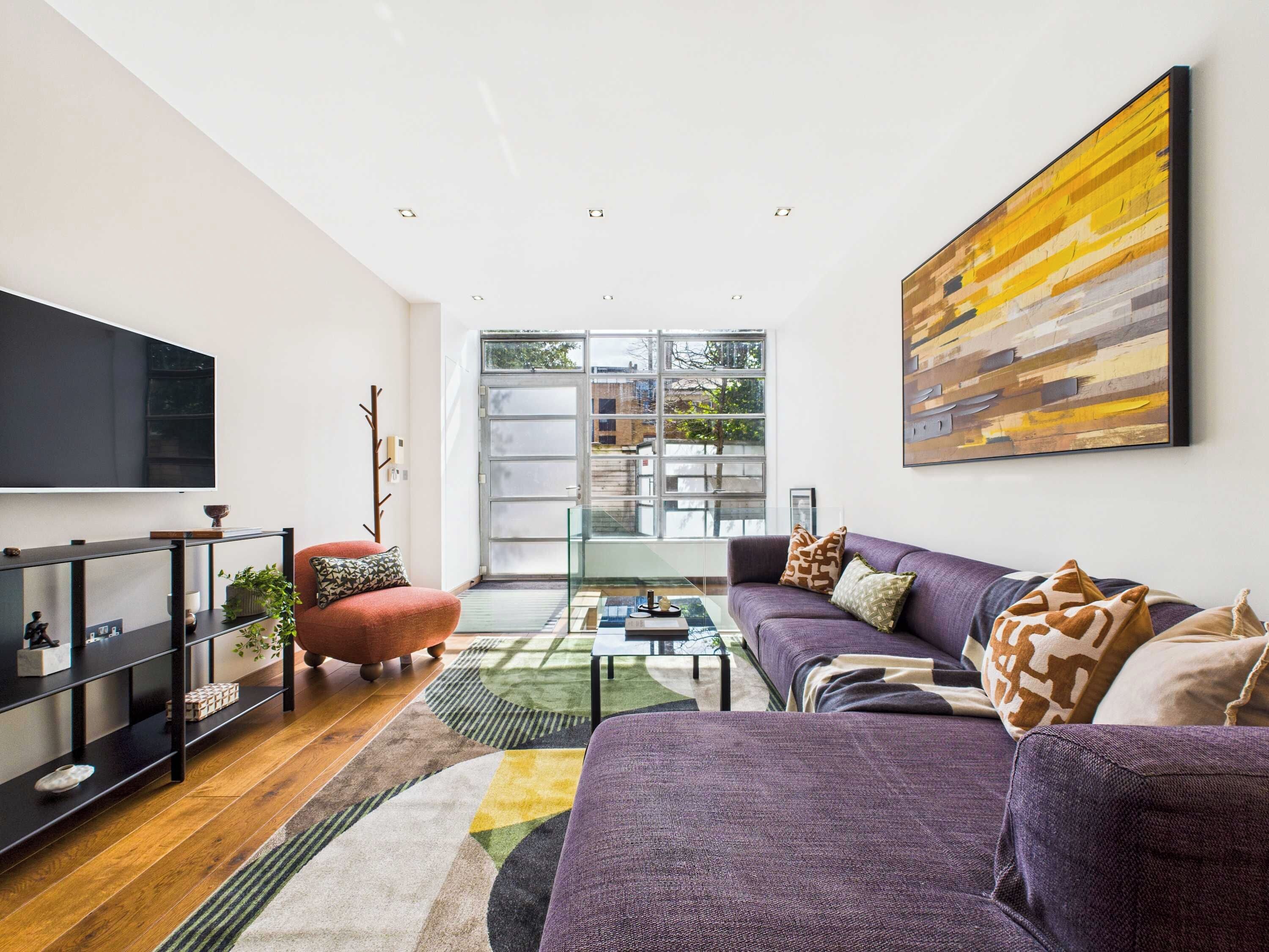 A modern living room with a large TV, a sofa, a coffee table, and a bookshelf.