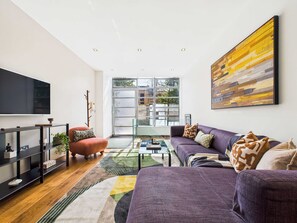 Un salon moderne avec une grande télévision, un canapé, une table basse et une bibliothèque.