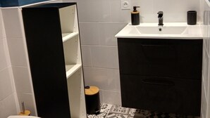 A bathroom with a white sink, black cabinet, and blue walls. - Blue room 4 persons (Poyanne)