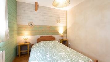 Une chambre à coucher comprenant un lit, deux tables de chevet, un luminaire suspendu et un mur orné d’un panneau en bois.