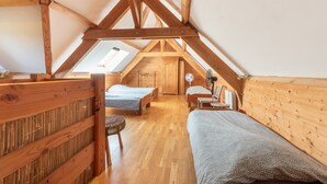 A loft-style bedroom with wooden beams, a skylight, and two beds.