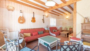 A cozy room with wooden walls, a red sofa, a green coffee table, and a guitar.