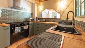 A kitchen with a stove, oven, microwave, sink, and wooden cabinets.