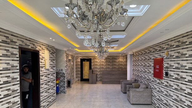 Um hall amplo com lustre, paredes em azulejo e balcão de recepção.