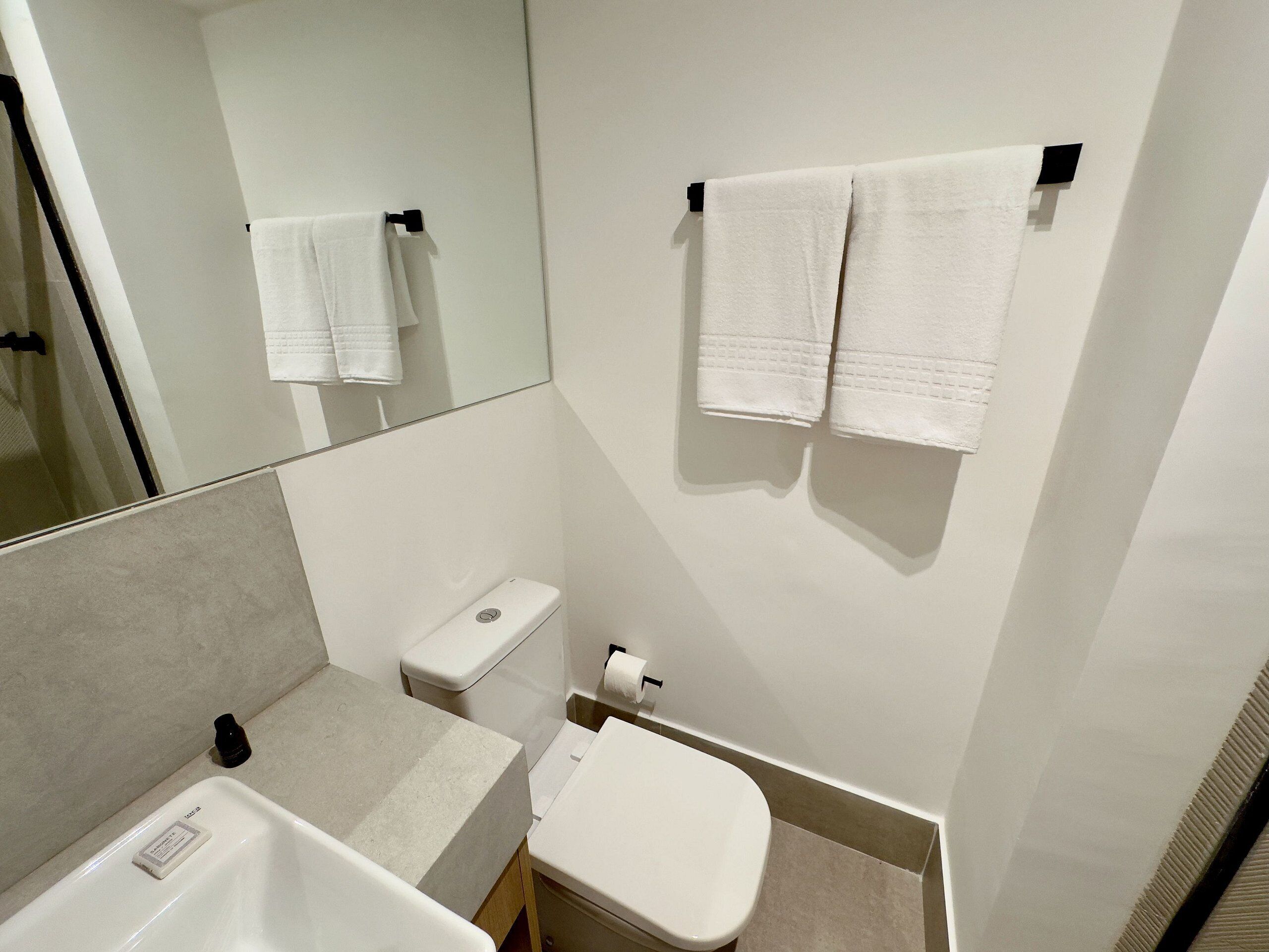 A compact bathroom with a white sink, toilet, and towel rack.