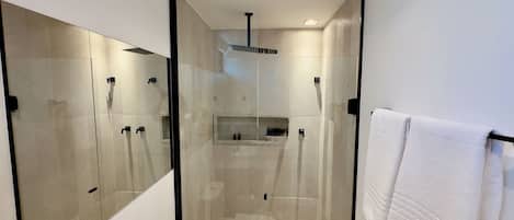A modern bathroom with a glass-enclosed shower, a toilet, and a towel rack.