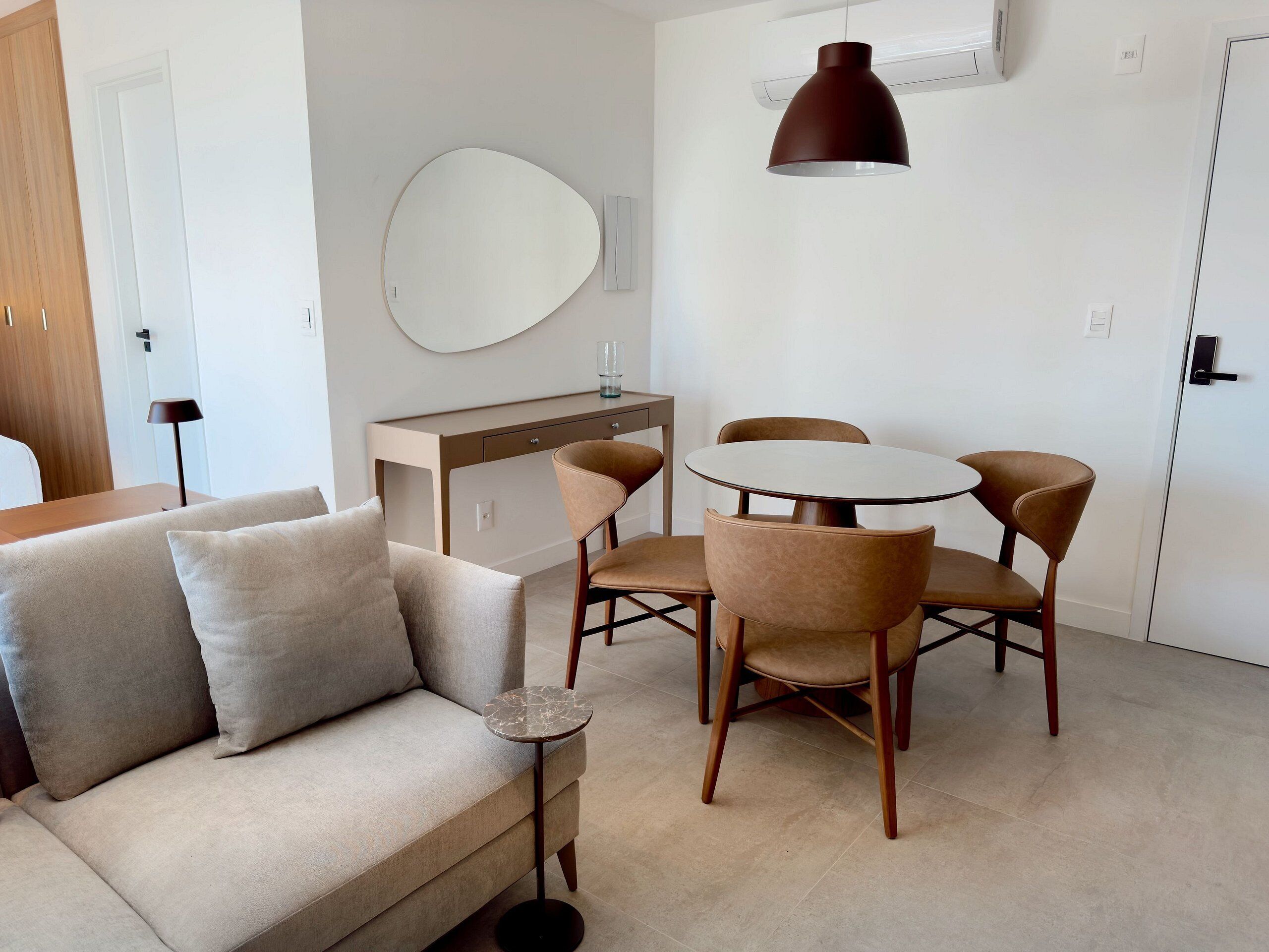 A modern living room with a sofa, a coffee table, and a dining area with chairs and a table.