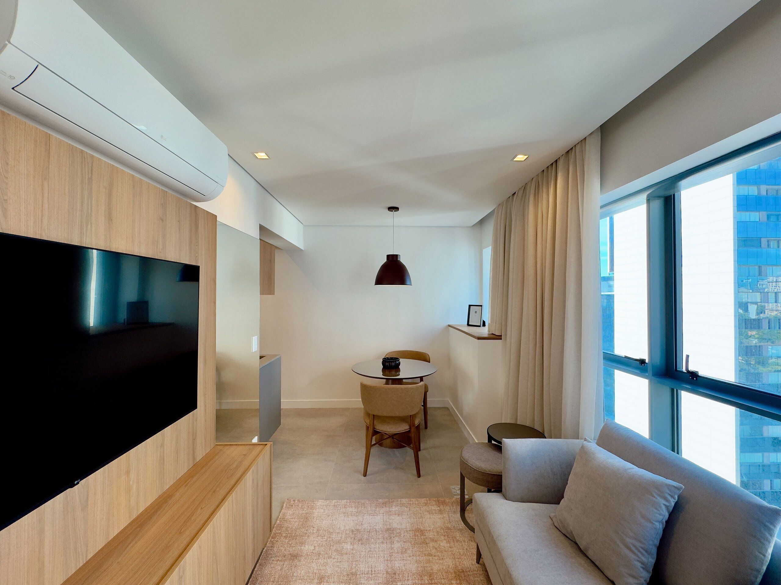 Una sala de estar moderna con un televisor de pantalla plana, un sofá, una mesita y una lámpara colgante.