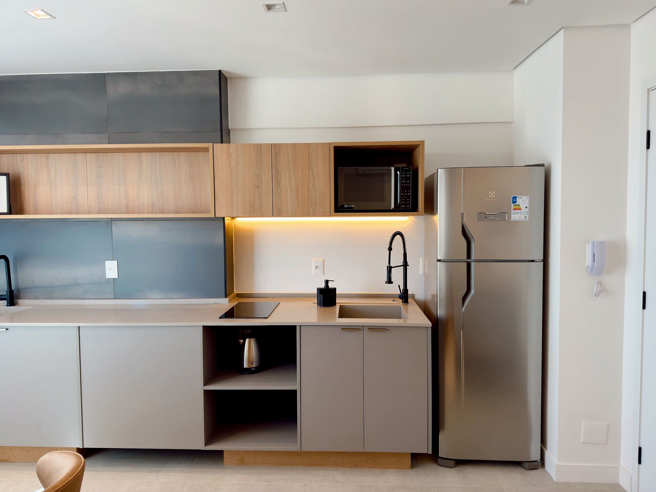 A modern kitchen with a stainless steel refrigerator, a microwave, and a sink.