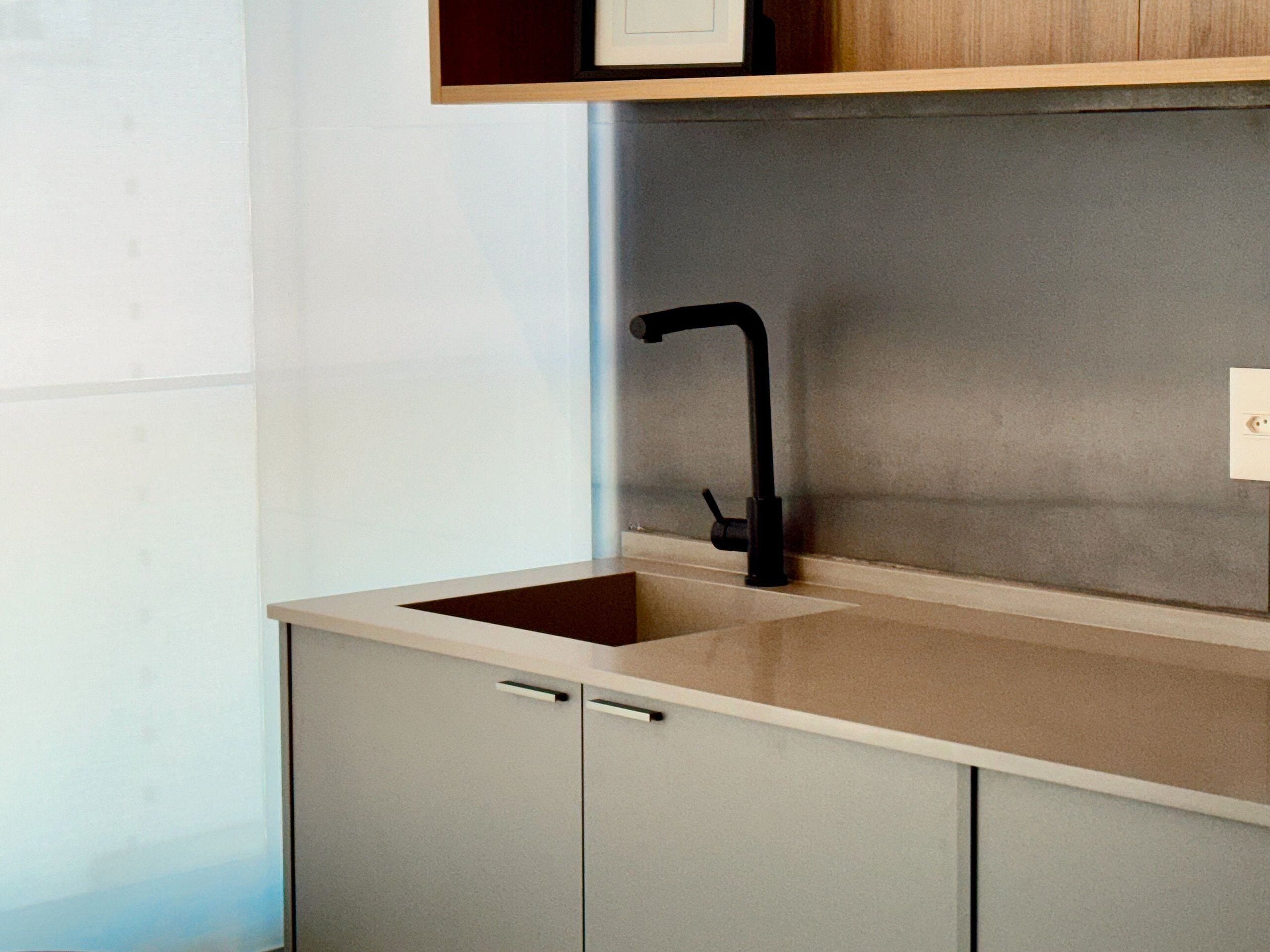 A modern kitchen with a single sink, a countertop, and a cabinet.