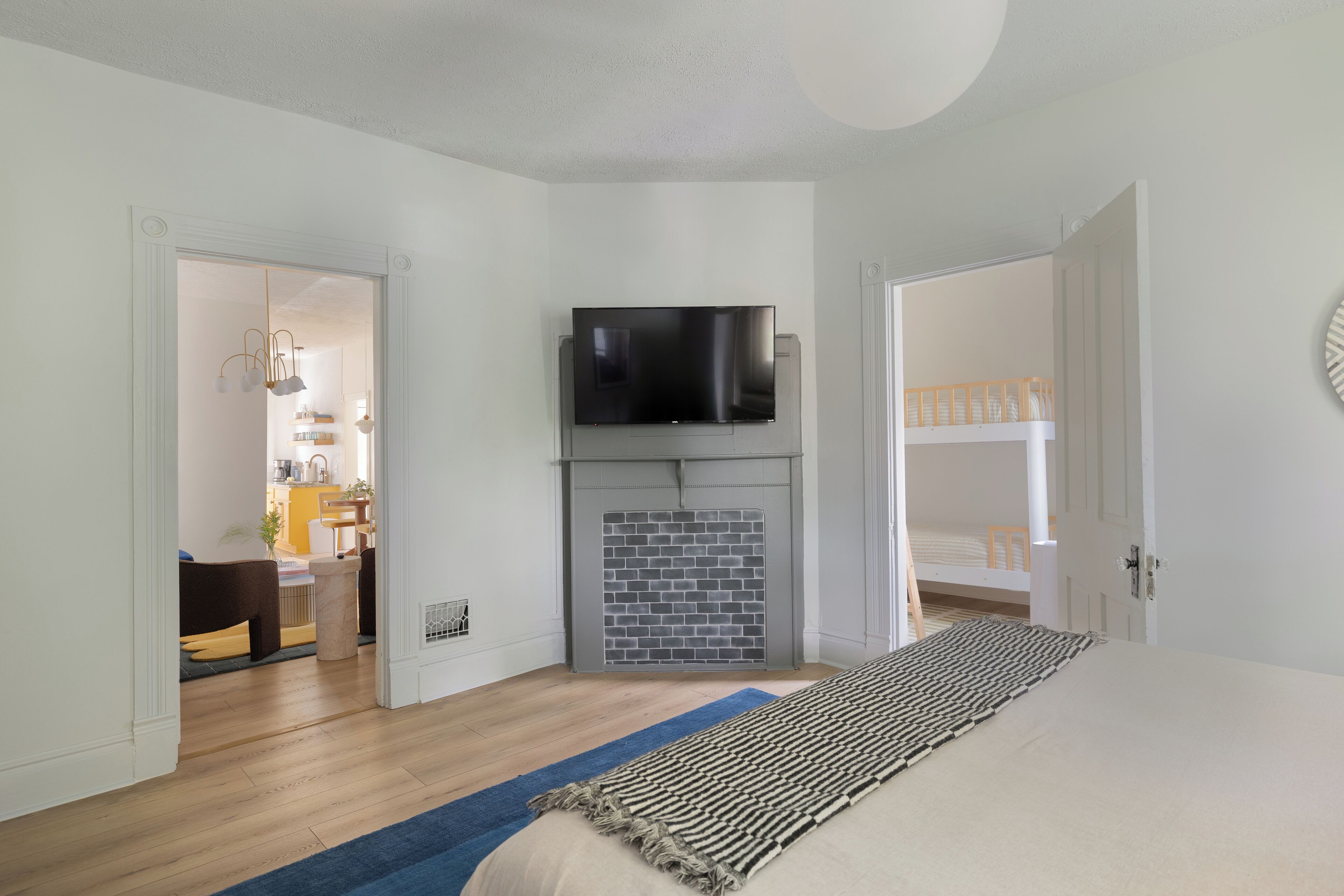 A bedroom with a bed, a TV mounted above a fireplace, and a door leading to a balcony.