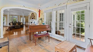 Ein geräumiges Wohnzimmer mit Klavier, Sofa und Essbereich mit einer Bank.