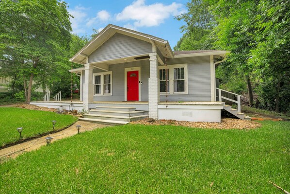 A single-story house with a red front door, white trim, and a covered porch.