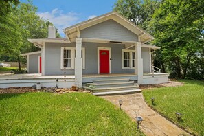 A two-story house with a red front door, a covered porch, and a stone pathway leading to the entrance. - Magnolia House Walk To Festival Park 3 Bedroom Home (Nacogdoches)
