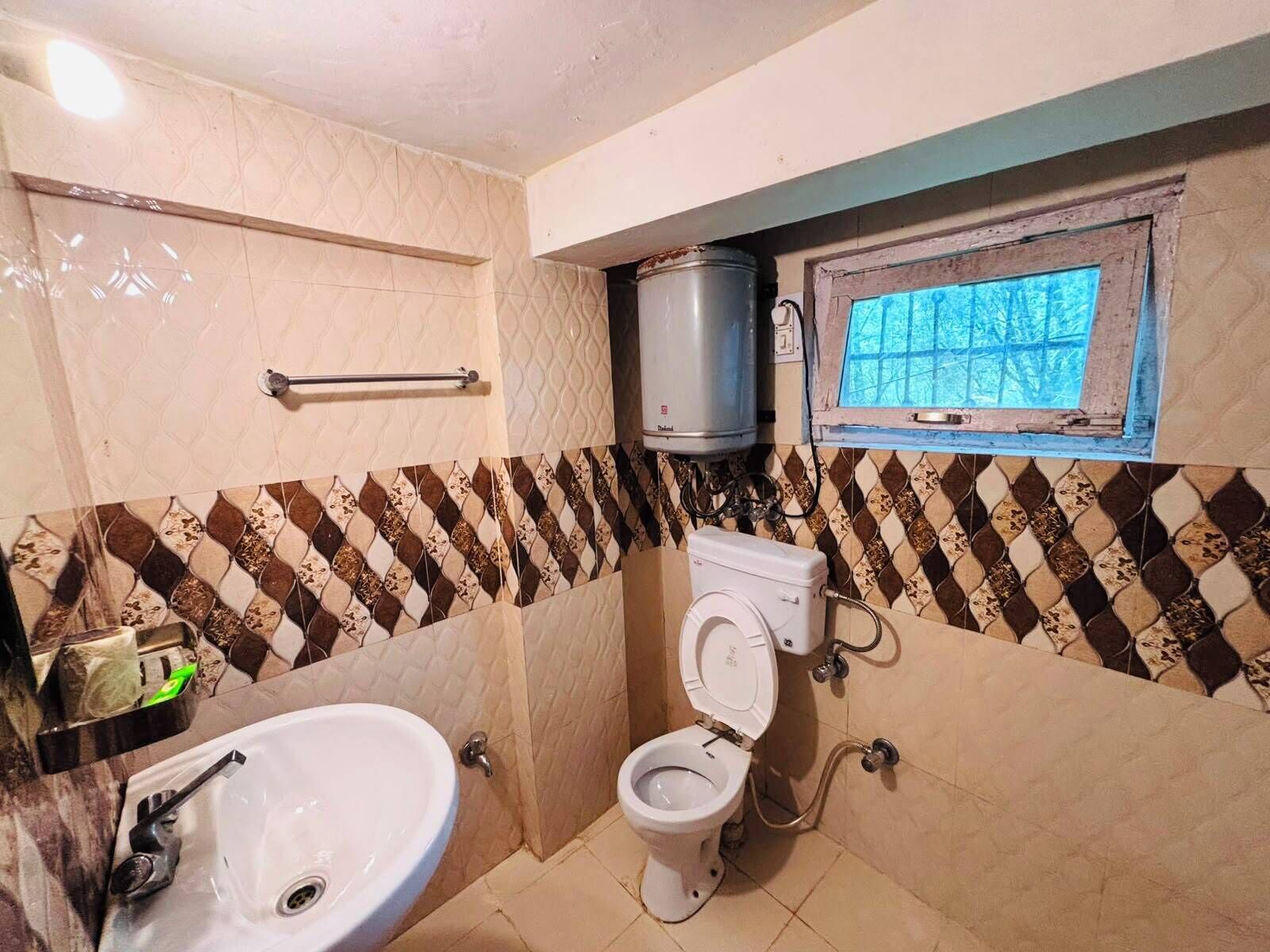 A bathroom with a toilet, sink, and a window above the toilet.
