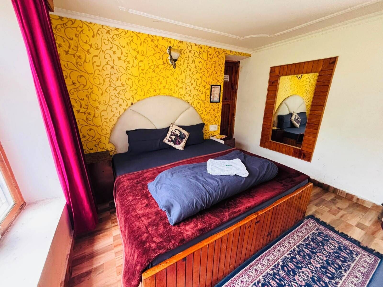 A bedroom with a bed, a mirror, and a patterned wall.